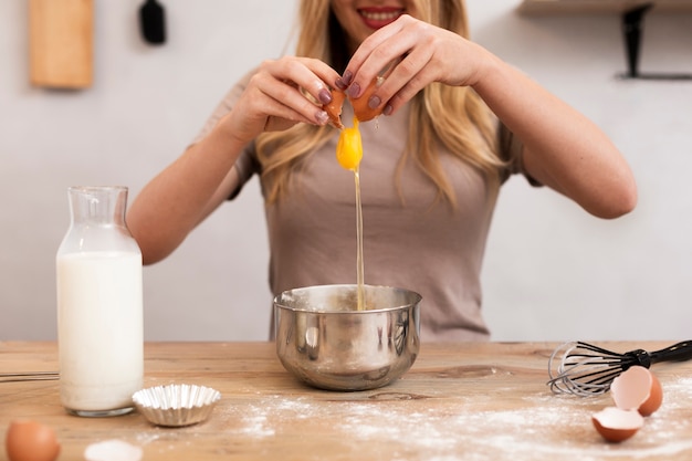 Smiling woman breaking egg in a metallic bowl