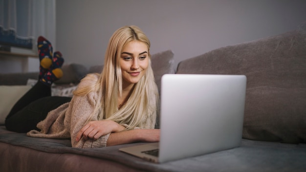 Smiling woman browsing laptop on couch