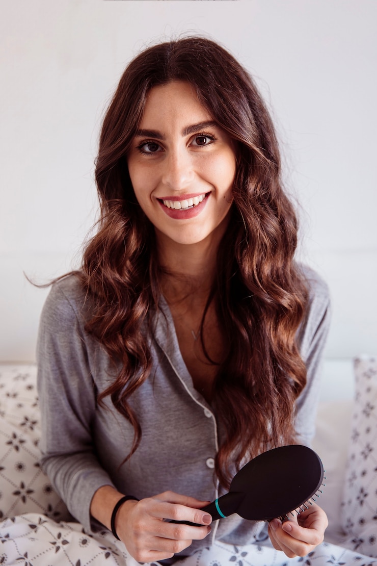 Free Photo smiling woman brushing hair in bed