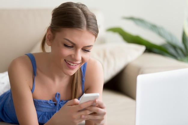 Free photo smiling woman calling friends while lying on sofa