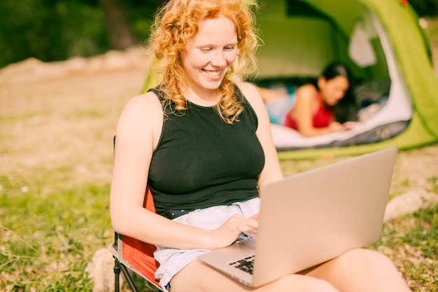 Donna sorridente che chiacchiera sul computer portatile all'aperto