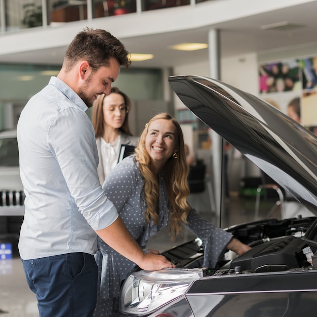 Foto gratuita donna sorridente che controlla il motore di automobile