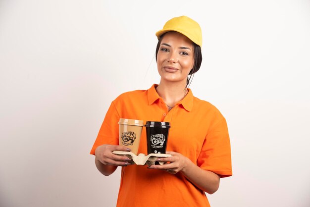 Smiling woman courier holding two cups of coffee