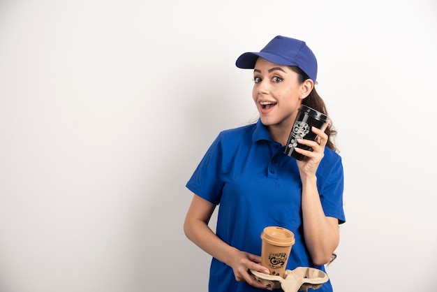 Smiling woman courier with two cups of coffee. High quality photo