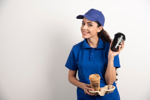 Smiling woman courier with two cups of coffee. High quality photo