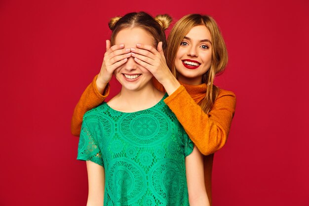 Smiling woman covering eyes with hands to her friend