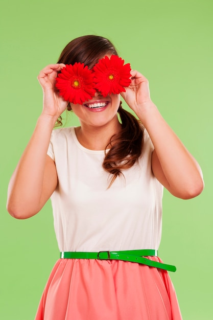 Foto gratuita donna sorridente che copre gli occhi con due fiori