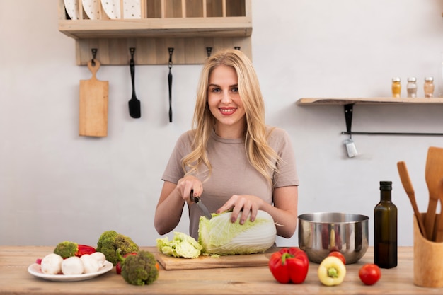 Free photo smiling woman cutting the iceberg cabbage