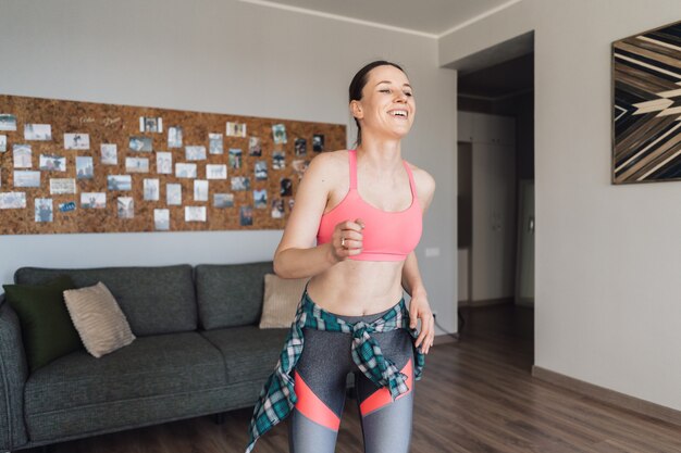 Smiling woman dancing in the middle of the living room enjoying herself and life