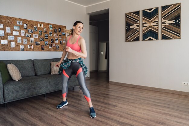 Smiling woman dancing in the middle of the living room enjoying herself and life