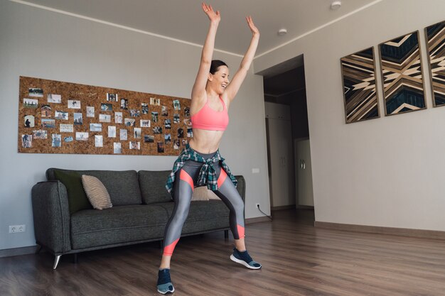 Smiling woman dancing in the middle of the living room enjoying herself and life