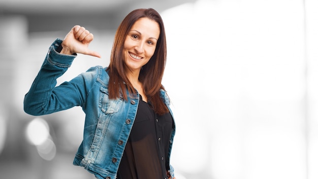 Donna in denim giacca sorridente che punta a se stessa