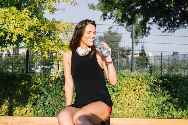 Smiling woman drinking water at outdoors