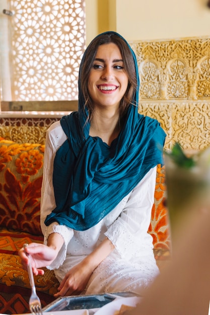 Smiling woman eating in arab restaurant