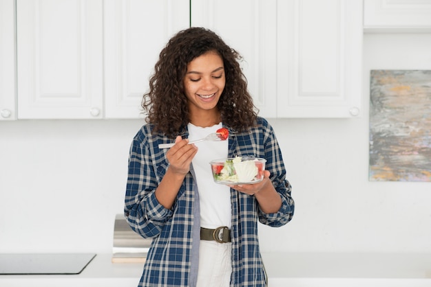 Free photo smiling woman eating healthy salad