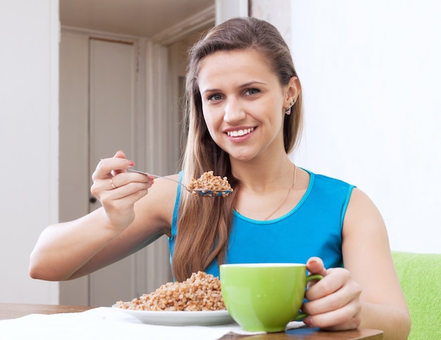 Free photo smiling woman eats buckwheat cereal