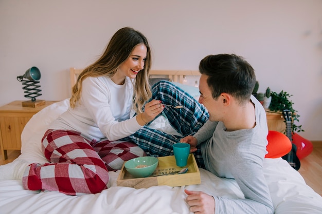 Foto gratuita donna sorridente che alimenta uomo a letto