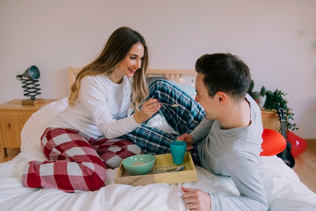 Smiling woman feeding man in bed