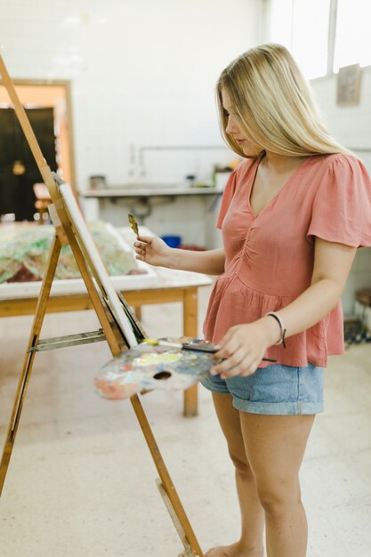 Smiling woman female artist painting artwork at workspace