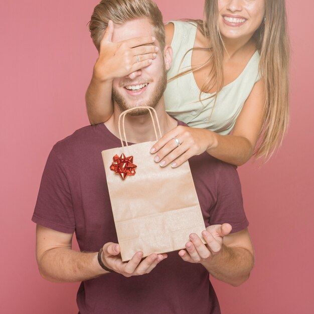 Smiling woman giving shopping gift bag to her boyfriend