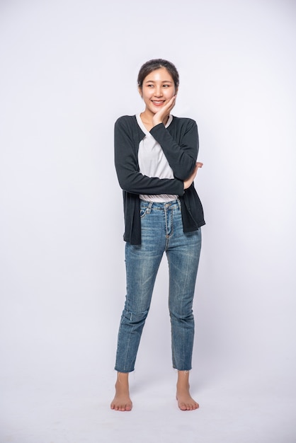 A smiling woman happily in a black shirt, standing jeans, smiling happily.