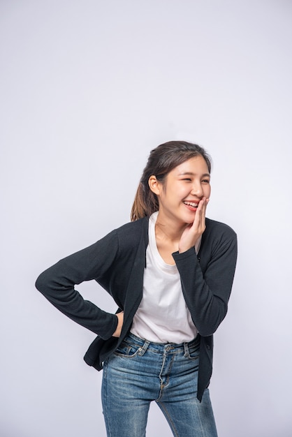 Free photo a smiling woman happily in a black shirt, standing jeans, smiling happily.