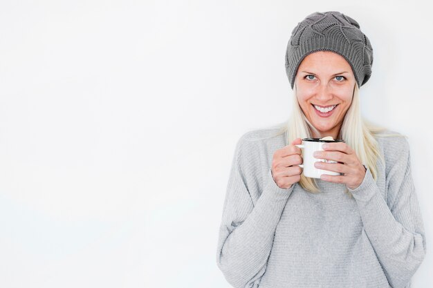 Smiling woman in hat holding hot drink