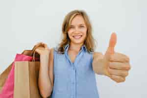 Free photo smiling woman holding bags and showing thumb up