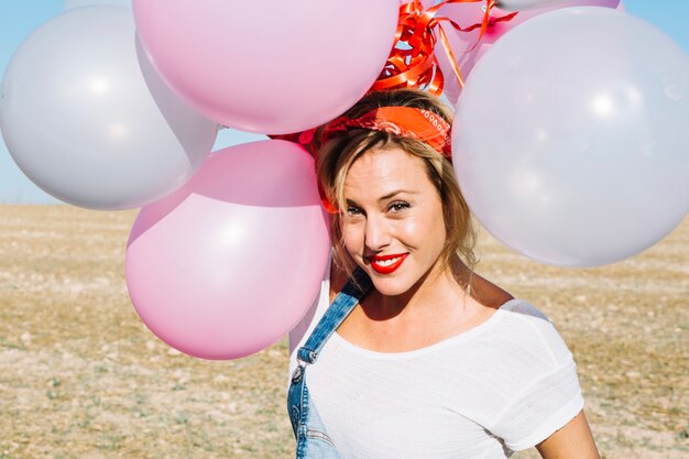 Smiling woman holding balloons over head