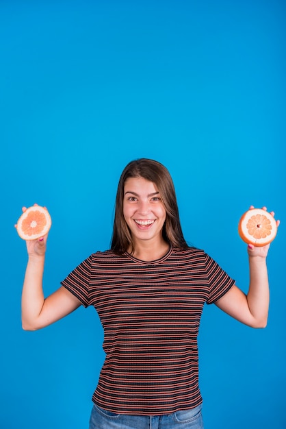 Free photo smiling woman holding cutting parts on grapefruit