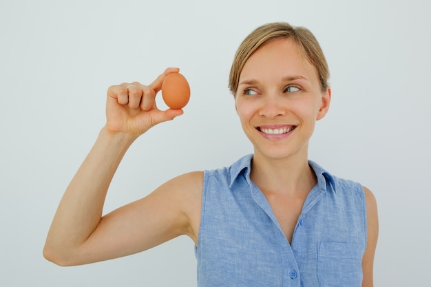 Smiling Woman Holding Egg With Two Fingers