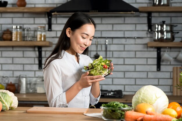 smiling woman holding glass of bowl with salad