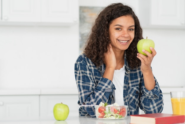 Foto gratuita donna sorridente che tiene una mela verde