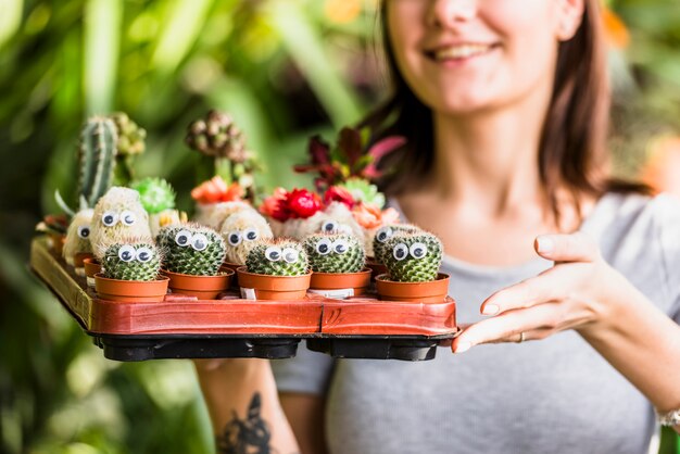 Smiling woman holding tray with green cactuses