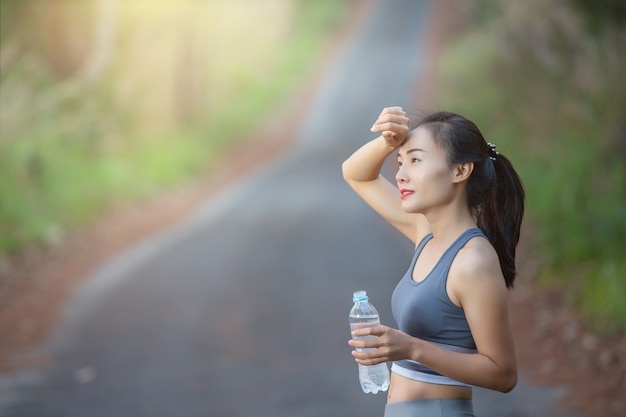 水のボトルを保持している女性の笑みを浮かべてください。