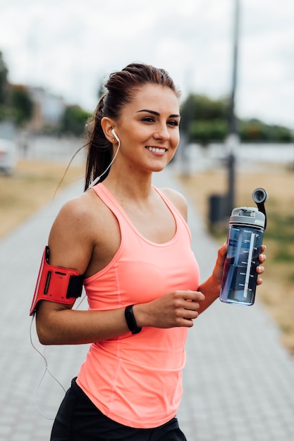 Foto gratuita donna sorridente che tiene una bottiglia di acqua