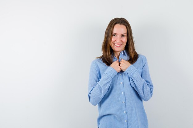 The smiling woman is clasping her hands on chest on white background