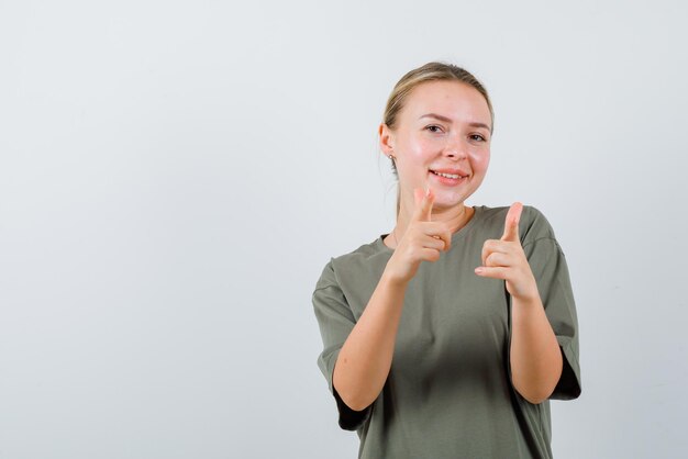 The smiling woman is pointing to camera with forefingers on white background