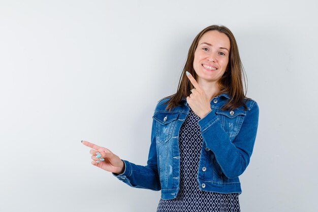 The smiling woman is pointing to left with forefingers on white background