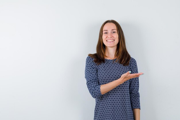 The  smiling woman is pointing to right with hand on white background