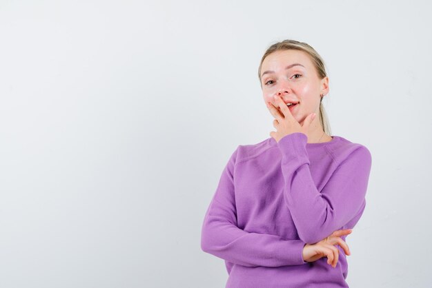 The smiling woman is putting her hand on mouth  on white background