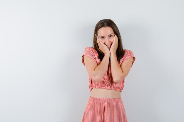 The smiling woman is putting her hands on cheeks on white background