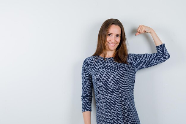 The smiling woman is raising up her muscle  on white background