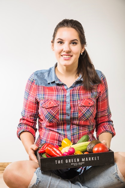 Улыбающаяся женщина, держащая овощи на коленях