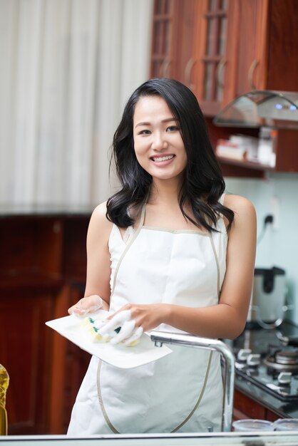 Smiling woman in kitchen washing dishes