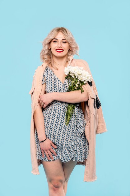 Smiling woman in light coat holding flowers