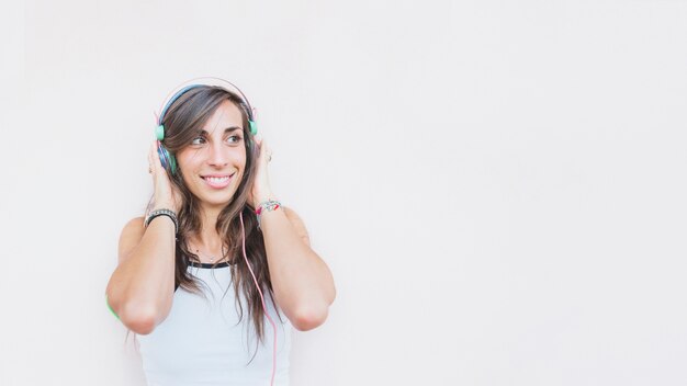 Smiling woman listening music on headphone against white background