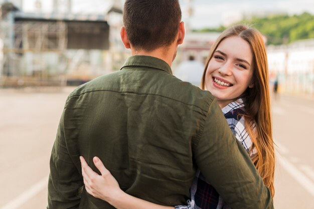 Smiling woman looking at camera while hugging her boyfriend