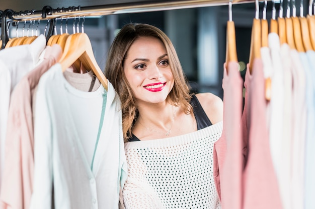 店で熊手に掛かっている服を見て笑顔の女性