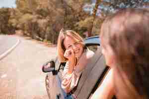 Free photo smiling woman looking at friend in car